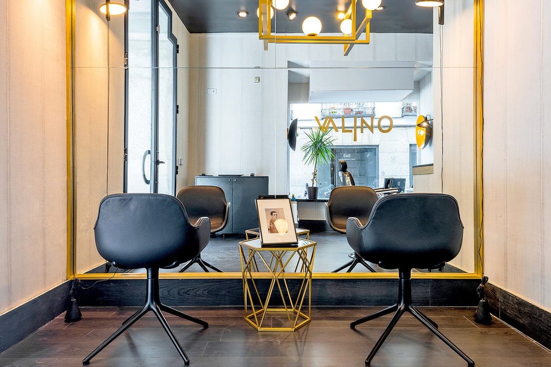 Sala de espera de Valino Hair con butacas de piel negra y mesa hexagonal de latón